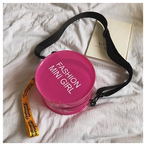 Close-up of pink transparent PVC round crossbody bag with adjustable black strap and ribbon