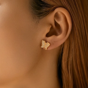 Minimalist gold butterfly earrings with zircon pavé wings worn by a model