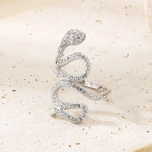 Macro shot of silver snake ring with pavé crystals on a textured stone background