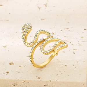 Gold snake ring with sparkling crystals on textured stone surface, elegant coiled design