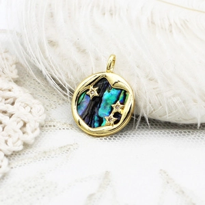 Macro view of a 18k gold-plated round pendant with abalone shell inlay and zircon stars