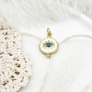 Macro detail of gold evil eye pendant with blue gemstone and micro-pave crystals