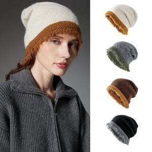 Close-up of winter knit beanies with raw fringe edges in various neutral color palettes