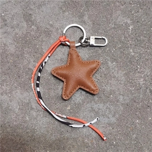 Detailed view of star-shaped brown leather keychain with silver metal ring and webbing