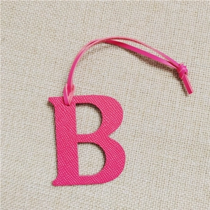 Pink letter B leather bag charm with lychee pattern and lanyard on linen