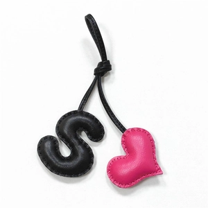 Handmade leather S-letter and pink heart bag charm with black cord on white background