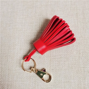 Detail showing high-quality red leather tassels with a golden metal clasp and ring