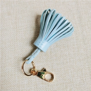 Detail of light blue leather tassel keychain with high-quality gold metal clasp