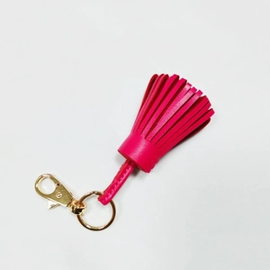 Detailed view of a bright fuchsia leather tassel keychain with gold-toned metal hardware