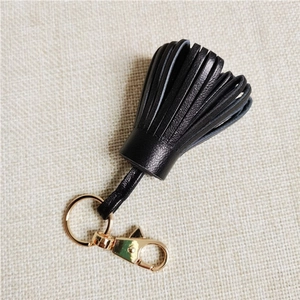 Macro detail of high-quality black leather tassel keychain with golden metal clasp