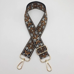 Close-up of adjustable jacquard bag strap with vintage floral pattern and gold hooks