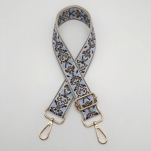 Detail of blue and brown ethnic jacquard bag strap with gold metal hooks and buckle