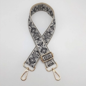 Close-up of black and grey jacquard bag strap with adjustable golden metal hardware