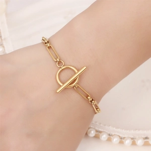 Golden stainless steel chain bracelet with T-bar OT clasp shown on a wrist with pearls