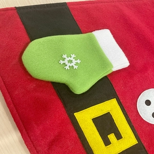 Festive Christmas table mat featuring red felt glove design with green snowflake and belt