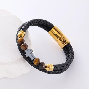 Braided leather bracelet with tiger eye beads and grey cross pendant on stone background