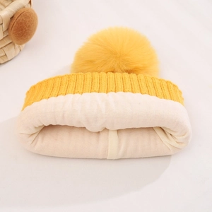Yellow kids knit winter hat with pompom and thick thermal lining on white background