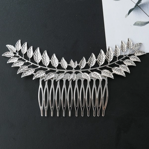 Silver hollow leaf hair comb with polished metallic veins on a textured background
