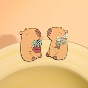 Set of two cartoon capybara enamel pins holding plants and flowers on orange background