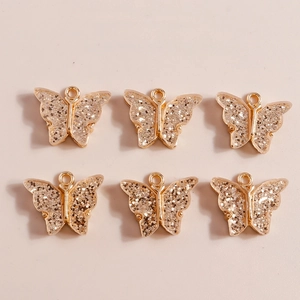 Macro shot of 6 gold alloy butterfly pendants with silver glitter for DIY jewelry making