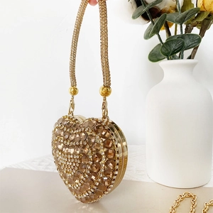 Detailed view of heart-shaped mini evening bag with champagne crystals and gold chain strap