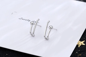 Detail showing minimalist silver paperclip style stud earrings with a polished finish