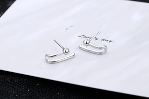 Detail view of silver paperclip earrings with polished metal beads and geometric C-shape