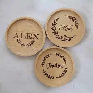 Close-up of circular wooden coasters with custom laser-engraved names and leaf patterns