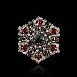 Detailed view of vintage baroque brooch featuring green center crystal and red gems
