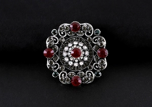Close-up of vintage baroque brooch with red crystals and antique silver hollow patterns