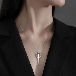 Detail of silver S925 geometric pendant necklace with minimalist vertical bar on model
