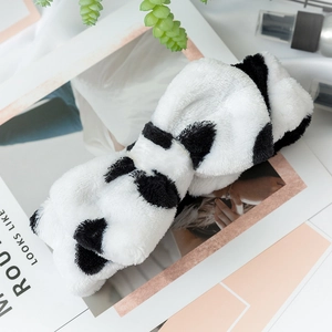 Detail of plush black and white panda headband on a lifestyle magazine background