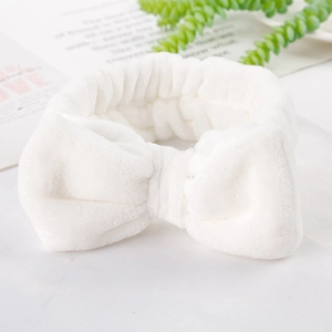 Close-up of a white plush coral fleece headband with a large soft bow for skincare