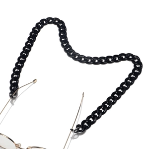 Close-up of black acrylic eyeglass chain with golden hardware on white background