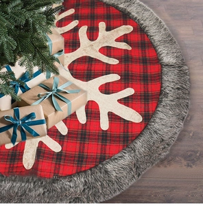 Detail of red and black plaid Christmas tree skirt with white antlers on wood floor