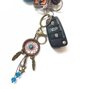 Handmade dreamcatcher keychain featuring blue beads and metal feathers on white background
