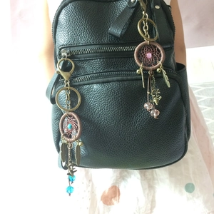 Detail of handmade dreamcatcher keychains with feathers and colorful beads on a black bag