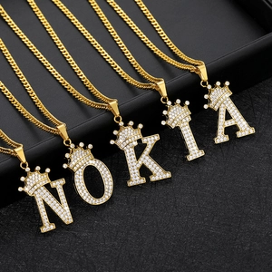Macro detail of 18k gold plated crown initial necklace with white zircon pavé setting