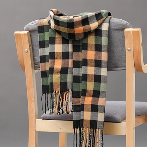Detailaufnahme eines karierten Strickschals mit Fransen in Schwarz, Grün und Orange