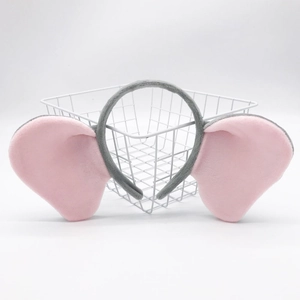 Close-up of grey and pink plush elephant ear headband on a white metal basket
