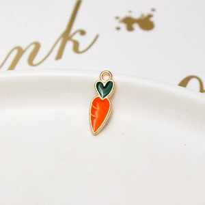 Macro shot of carrot-shaped alloy charm with orange enamel and green heart leaf