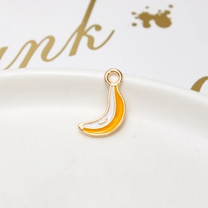 Detailed view of a yellow enamel banana pendant charm with a golden metal loop and trim