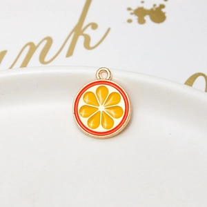 Detail of orange slice alloy pendant with gold plating on a white ceramic tray