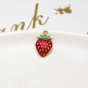 Macro shot of red strawberry pendant with gold seeds and green enamel details