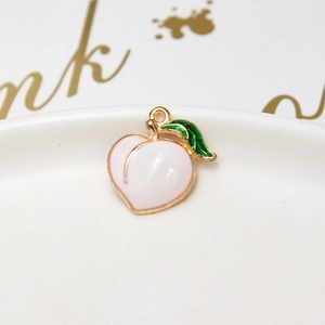 Macro shot of peach-shaped alloy pendant with pink enamel and gold-plated details