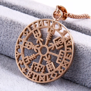 Macro shot of rose gold Viking compass pendant on a grey fabric background