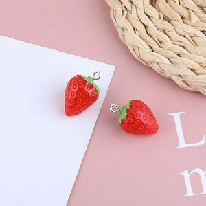 Detail of red resin strawberry charms with green leaves and metal rings for DIY jewelry