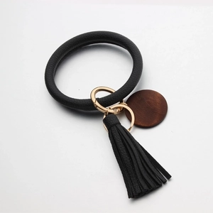 Close-up of black PU leather bracelet keychain with fringe tassel and wood charm