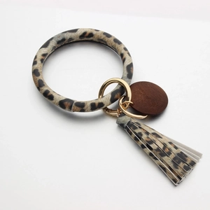 Leopard print leather keychain bracelet with wooden tag and matching tassel on white backdrop