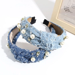 Two knotted denim headbands with artificial pearls and rhinestones on white surface